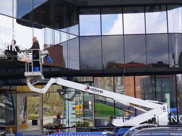 Fönsterputsare på GÖAB står i en skylift och putsar stora fönsterpartier på en kontorsbyggnad i Göteborg.