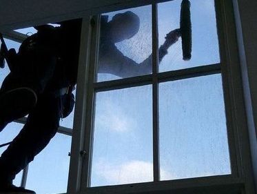 En fönsterputsare putsar utsidan av ett fönster, inifrån 